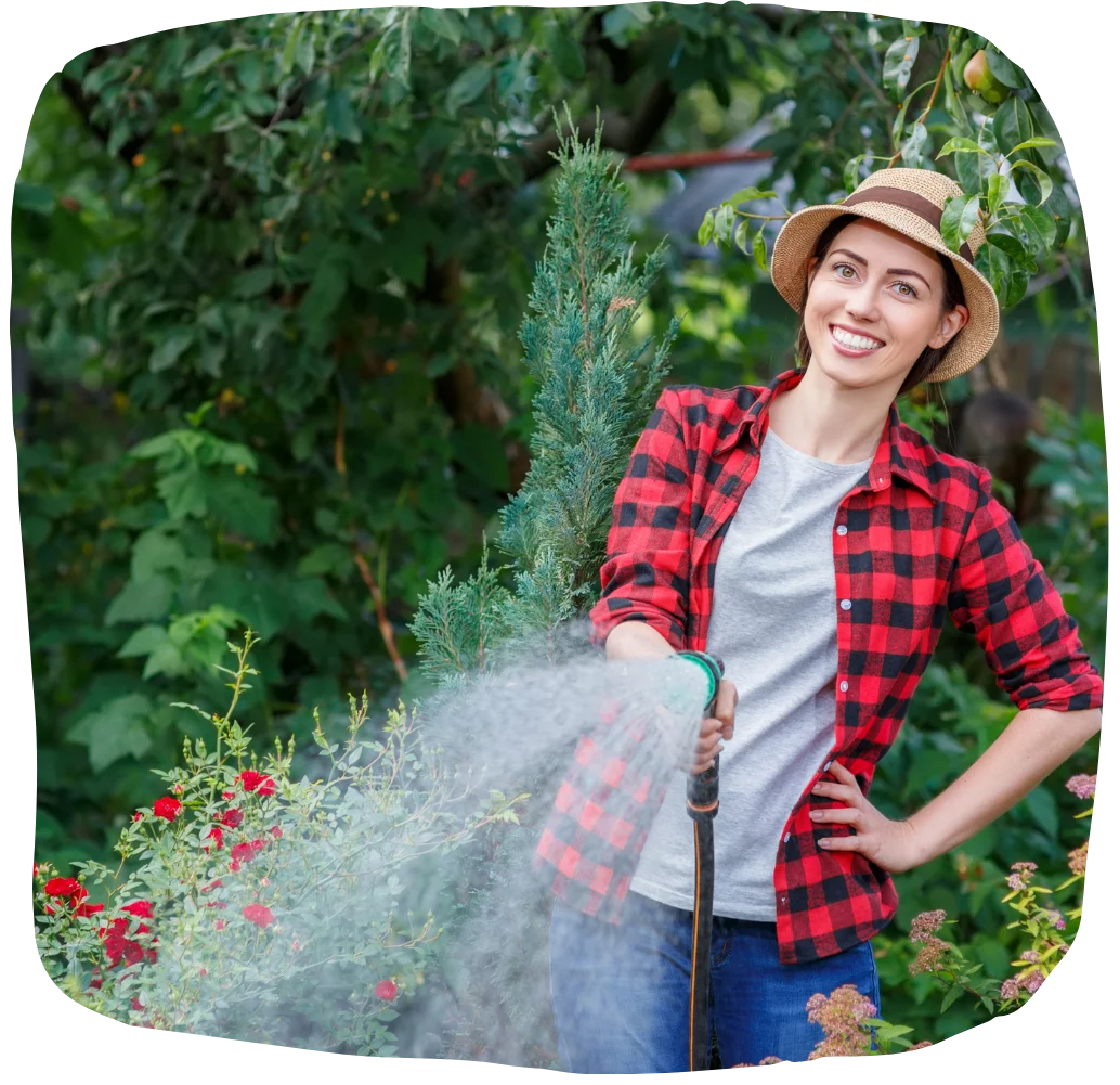Woman holding a hose watering a garden